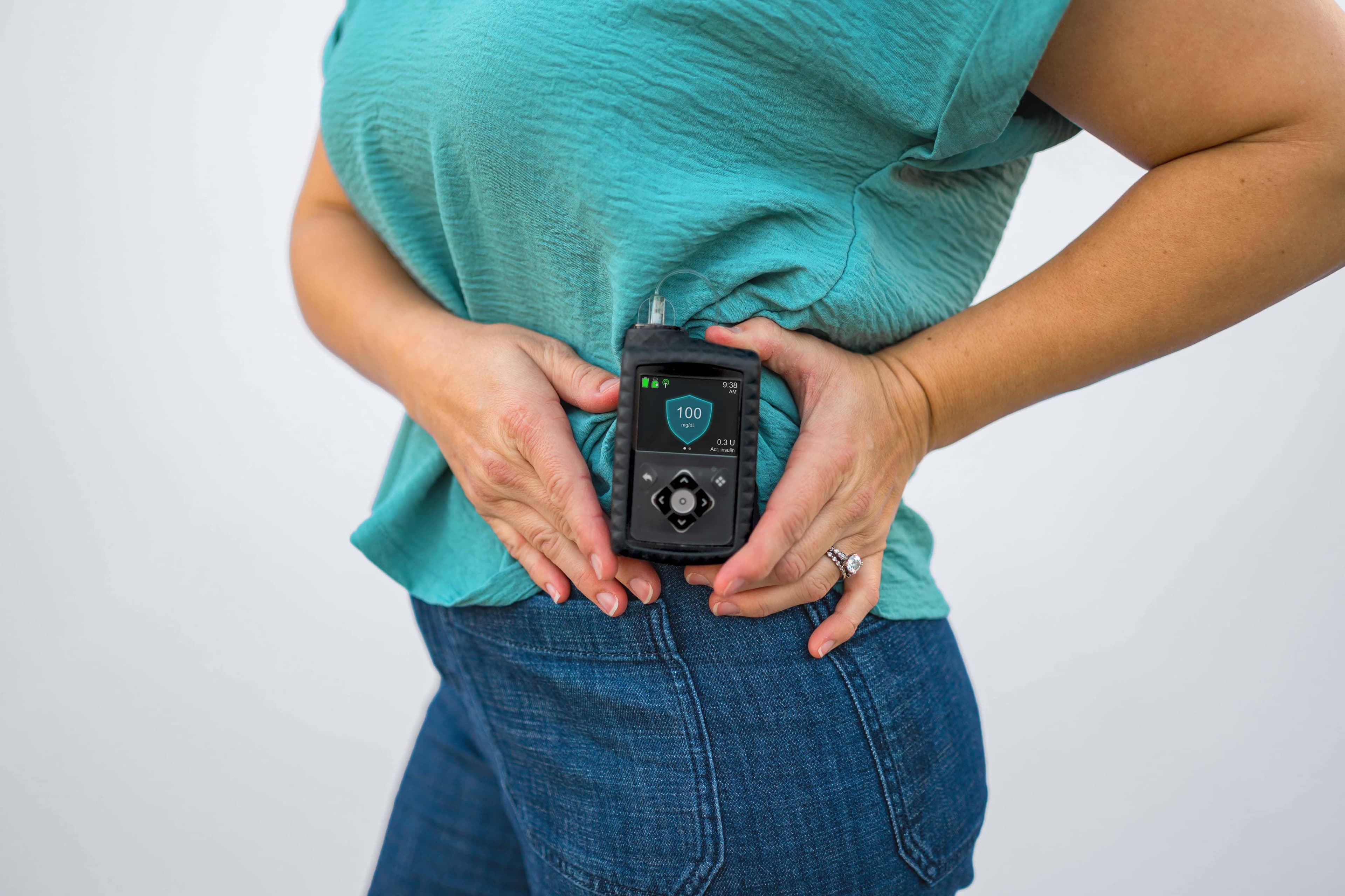 Person holding the MiniMed™ 780G insulin pump in both hands showing the front display screen