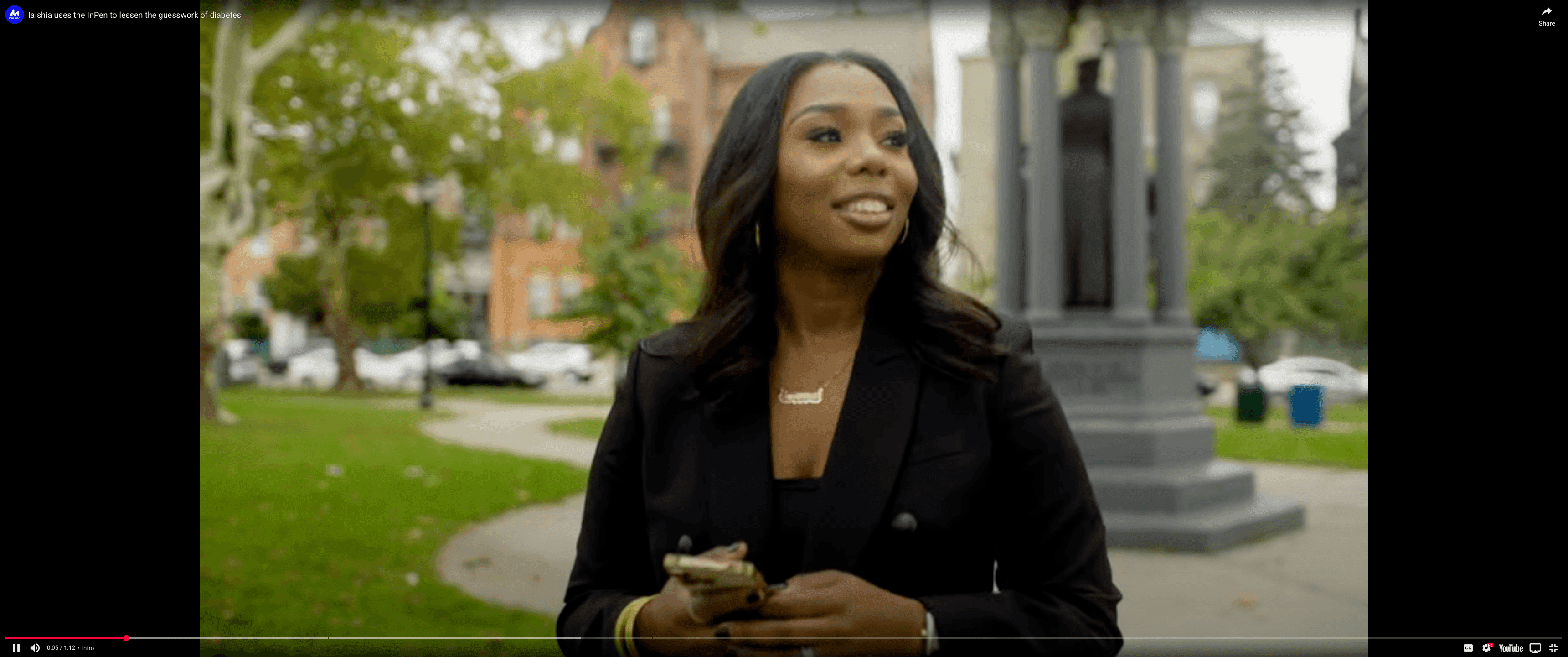 Iaisha, MiniMed™ Champion, smiling outdoors while holding a smartphone