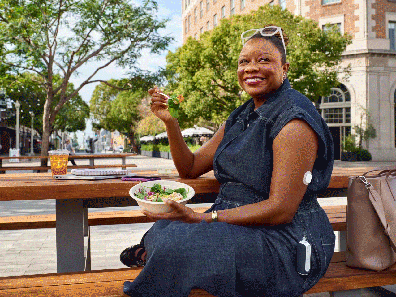 Woman eating lunch outdoors wearing MiniMed Flex and Simplera sensor