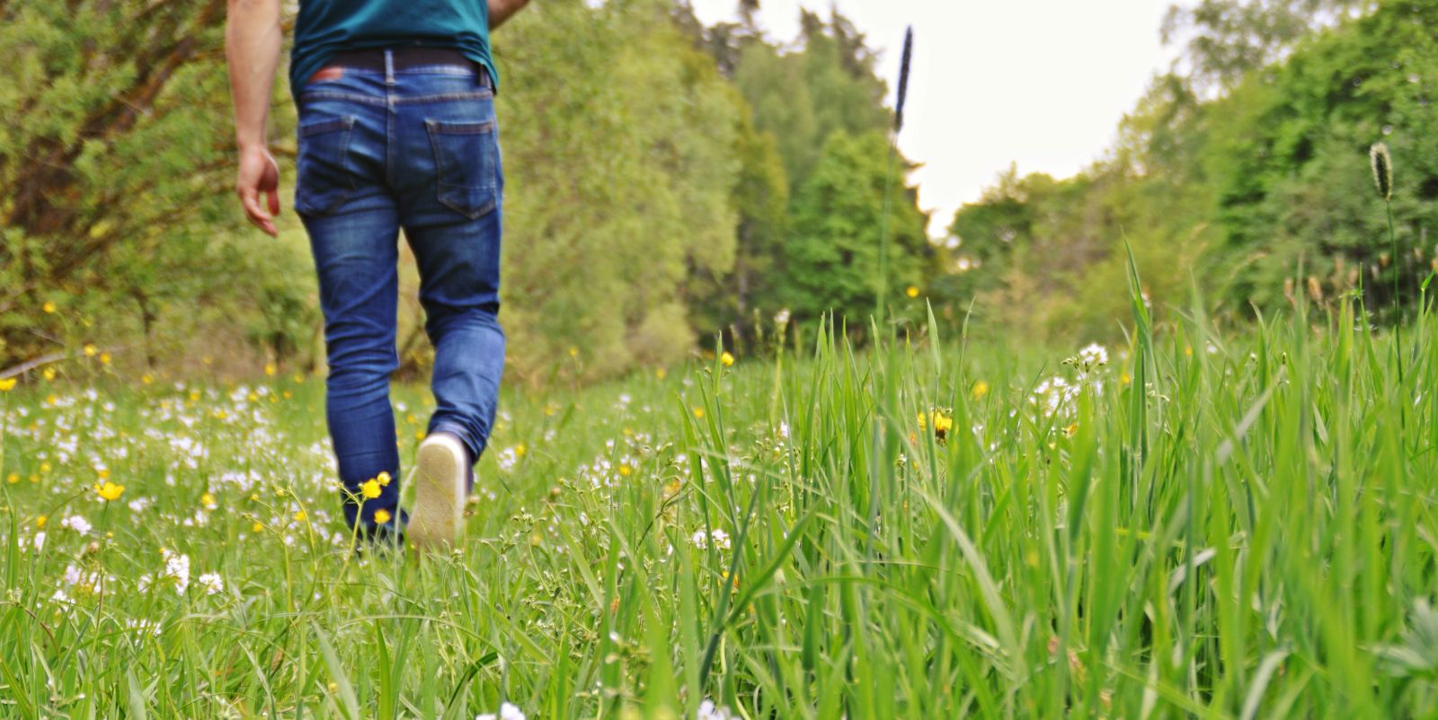 Man in jeans walking through grass