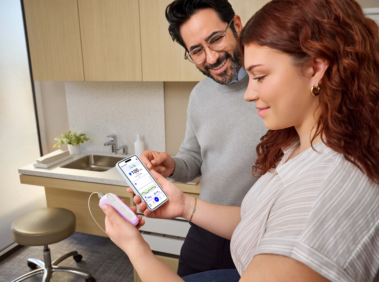 Woman holding MiniMed Flex and her smartphone in doctor office with doctor