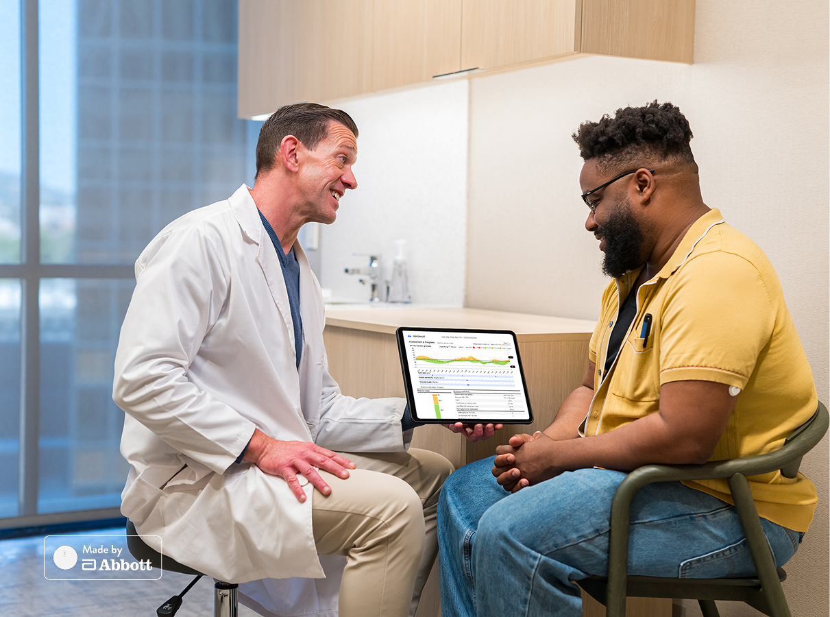 Man in a clinic office reviewing digital diabetes data with healthcare professional