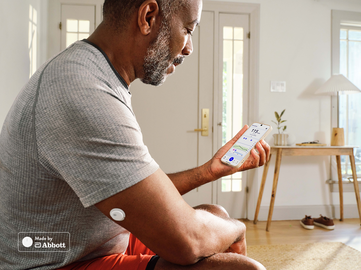 Man viewing MiniMed Go app on phone wearing Instinct sensor, made by Abbott