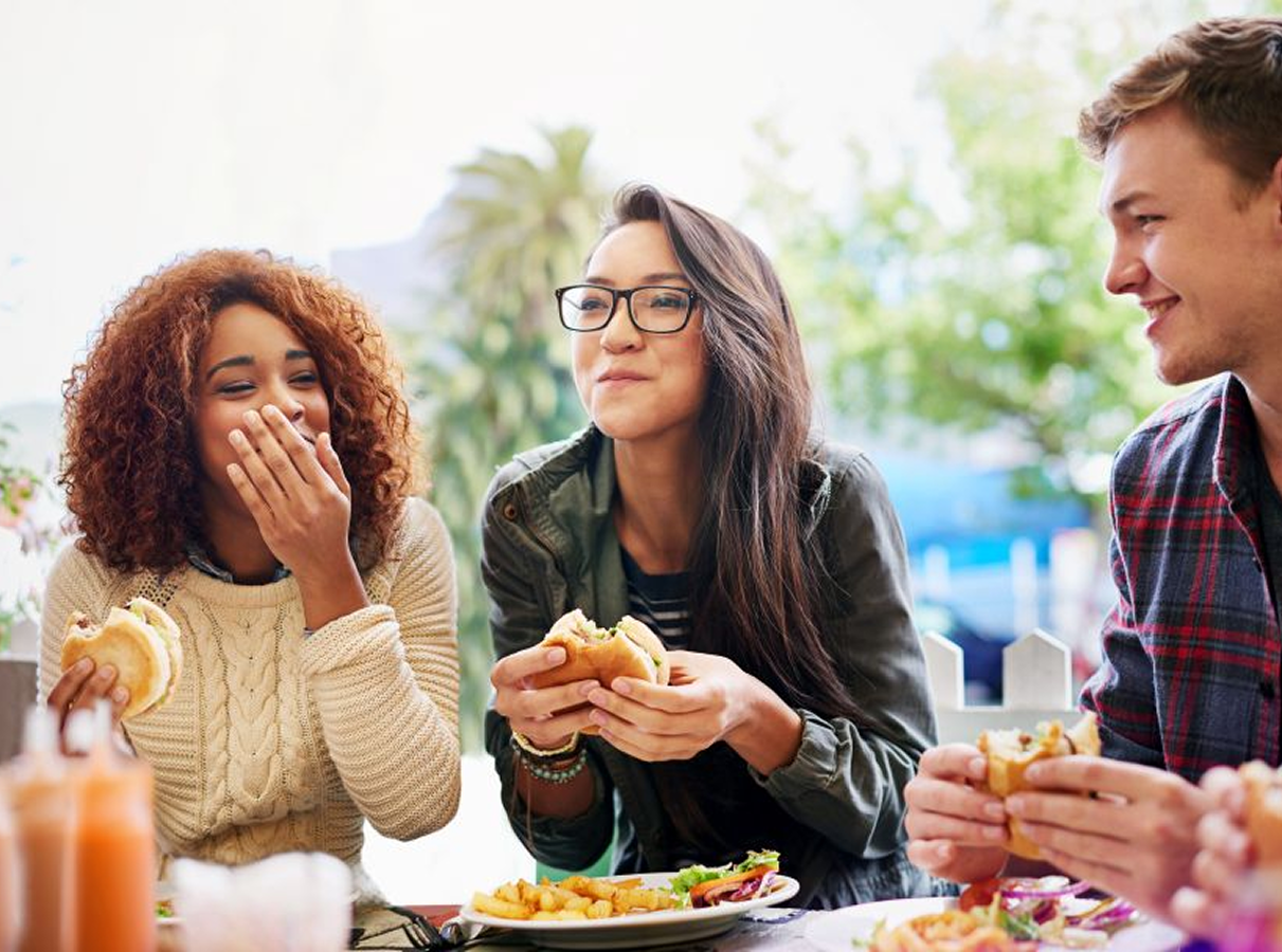 Woman eating a hamburger with friends