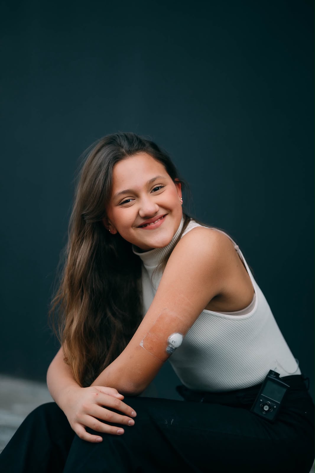 Valentina smiling wearing a continuous glucose monitor and insulin pump.