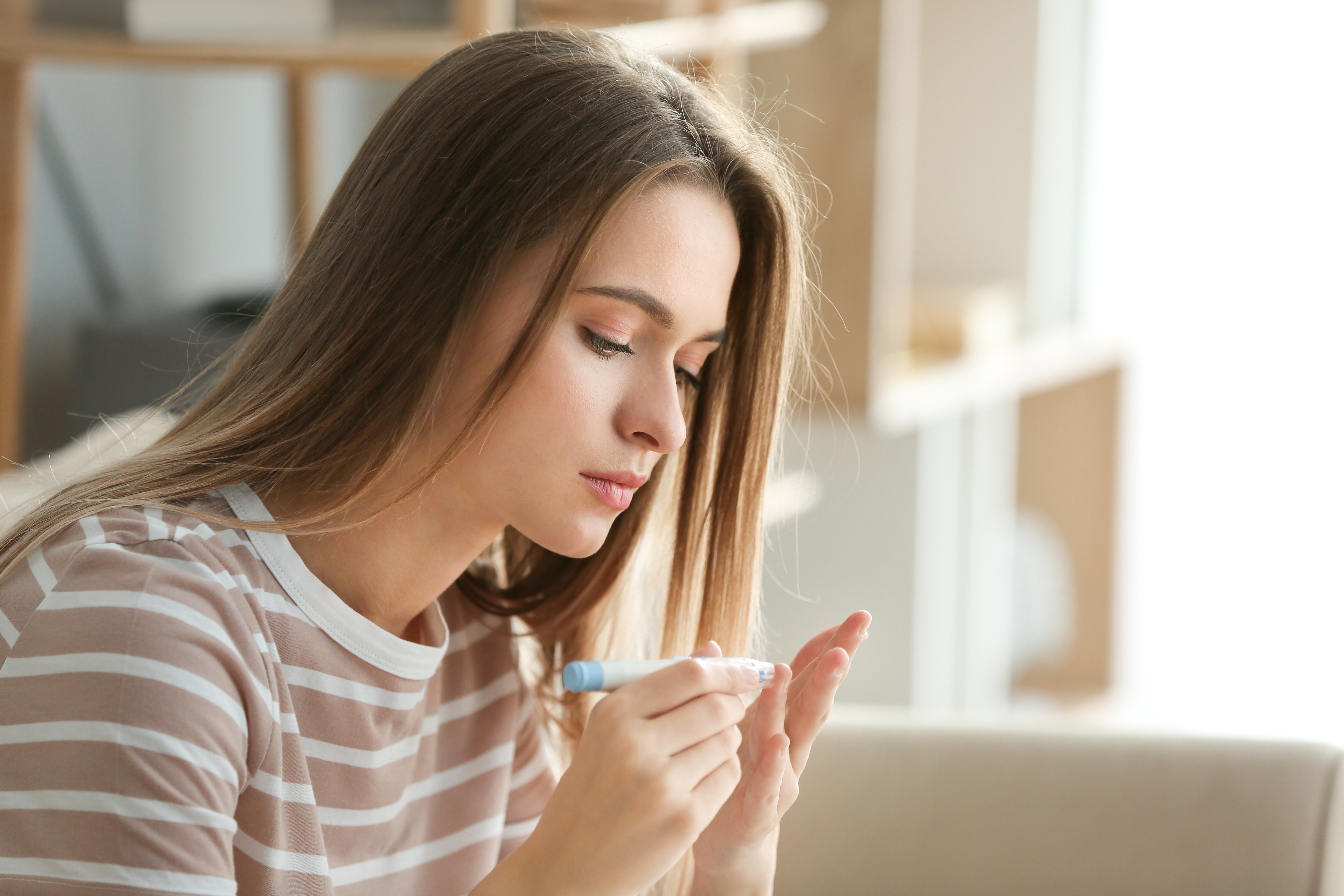Diabetic woman checking blood sugar level at home